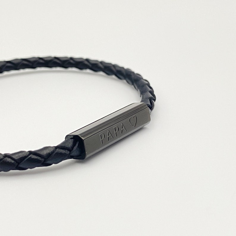 May include: Black leather bracelet with a black metal bar that says "PAPA" with a heart symbol.