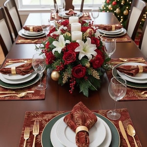 May include: A festive dining table set for a holiday meal. The table is adorned with white plates, gold silverware, and burgundy napkins. A floral centerpiece of red roses, white lilies, and candles adds to the celebratory atmosphere. A Christmas tree is visible in the background.