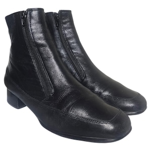 May include: A pair of black leather ankle boots with side zippers. The boots have a square toe design and a small heel. The leather appears to be slightly textured. The boots are set against a white background.