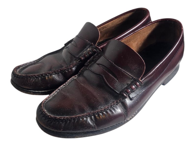 May include: A pair of dark brown leather loafers with a penny strap detail. The loafers have a classic design and are made of high-quality leather.