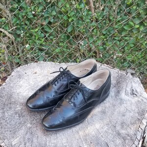Puede incluir: Un par de zapatos negros de cuero con cordones y detalles de punta de ala. Los zapatos tienen un dise&ntilde;o cl&aacute;sico de brogue y est&aacute;n en buen estado.