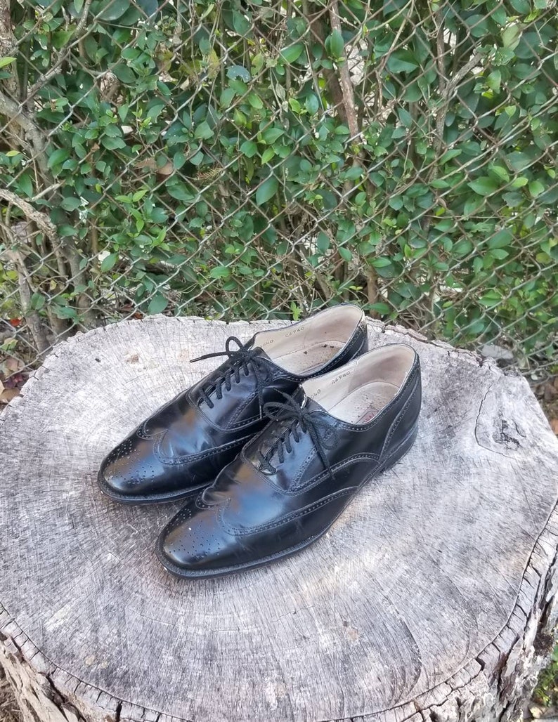 Puede incluir: Un par de zapatos negros de cuero con cordones y detalles de punta de ala. Los zapatos tienen un dise&ntilde;o cl&aacute;sico de brogue y est&aacute;n en buen estado.