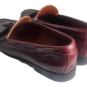 May include: A pair of burgundy leather loafers with tassels. The loafers have a classic design and are made of high-quality leather.