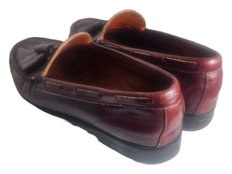 May include: A pair of burgundy leather loafers with tassels. The loafers have a classic design and are made of high-quality leather.