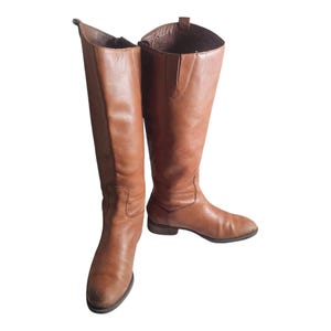 以下が含まれることがあります： ポインテッドトゥのブラウンレザーニーハイブーツのペア