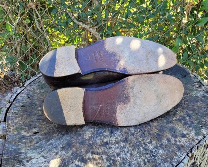 Pode incluir: Close-up das solas de um par de sapatos de couro marrom. Os sapatos t&ecirc;m uma sola de couro texturizada e uma parte superior de couro lisa.