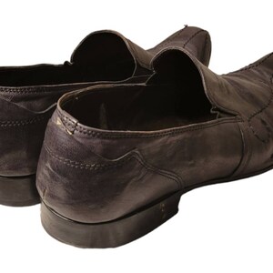 May include: A pair of dark brown leather slip-on shoes with a pointed toe and a stitched design.