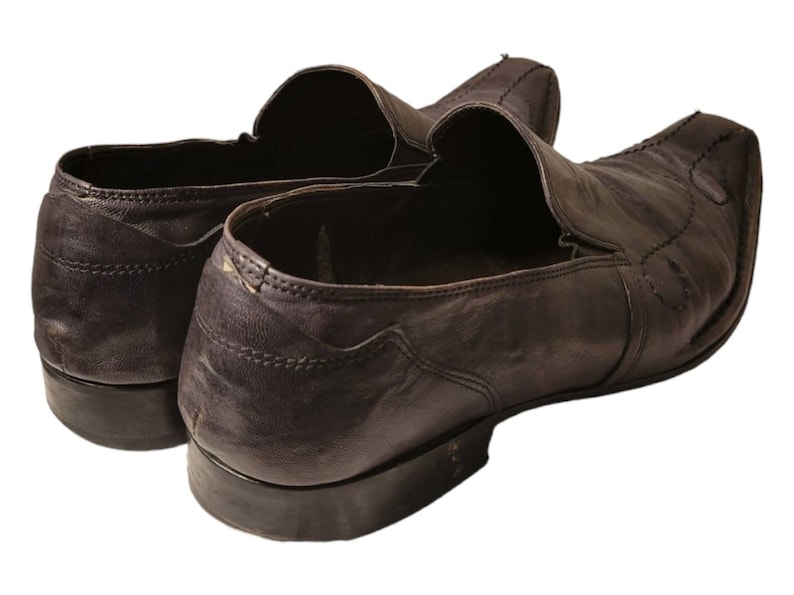 May include: A pair of dark brown leather slip-on shoes with a pointed toe and a stitched design.