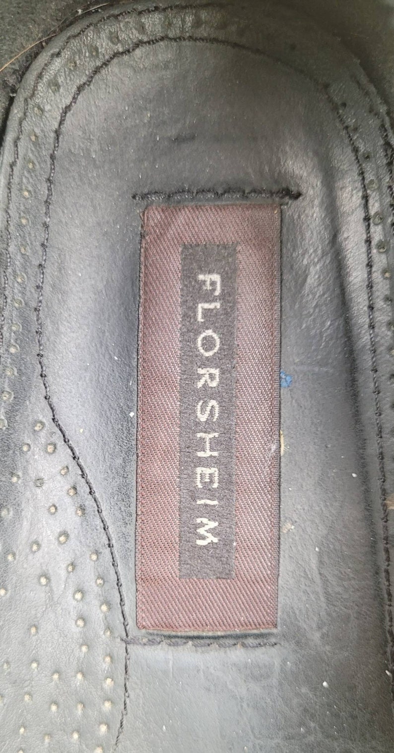 May include: Close-up of a brown leather insole with the word "FLORSHEIM" printed in white on a brown label.
