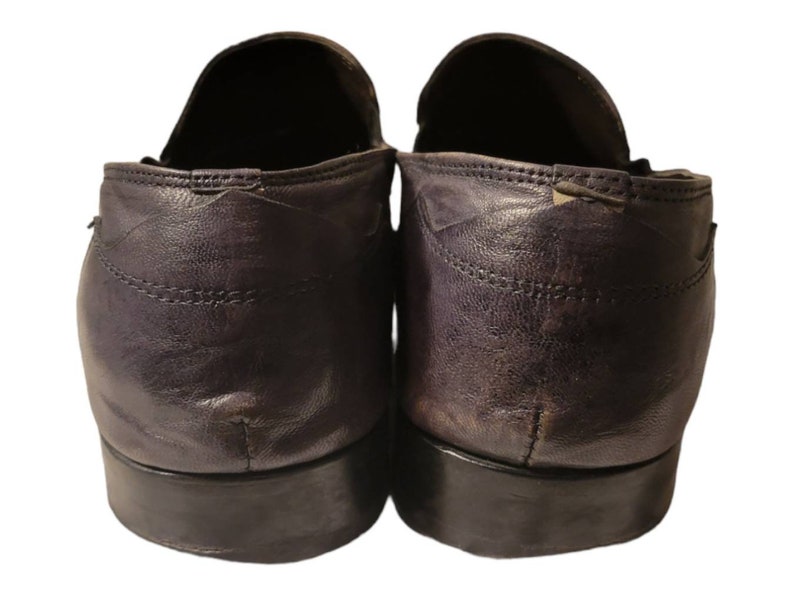 May include: A pair of dark purple leather loafers with a slightly worn look. The shoes have a rounded toe and a low heel.