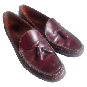 May include: A pair of brown leather tassel loafers. The loafers have a pointed toe and a tassel detail on the vamp.