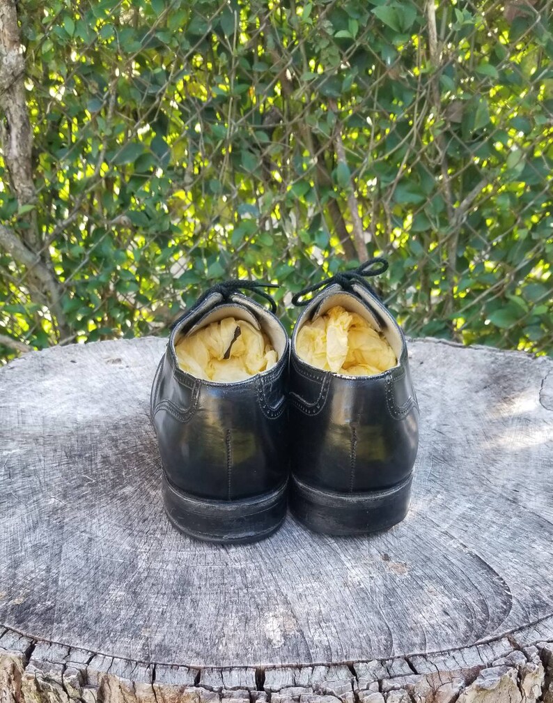 Puede incluir: Un par de zapatos de cuero negro con cordones, llenos de patatas fritas amarillas, sentados en un toc&oacute;n de &aacute;rbol.