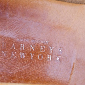 May include: Close-up of a brown leather insole with the text "MADE IN ITALY" and "BARNEYS NEW YORK" embossed in silver.