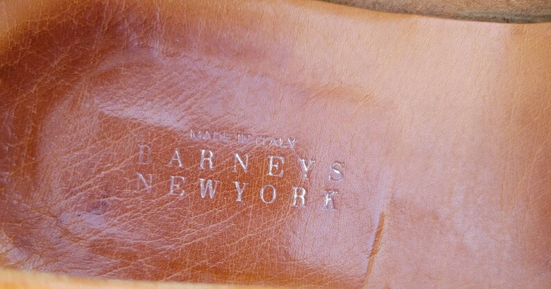 May include: Close-up of a brown leather insole with the text "MADE IN ITALY" and "BARNEYS NEW YORK" embossed in silver.