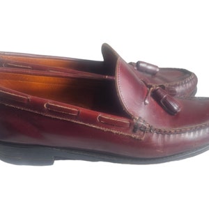May include: A pair of burgundy leather tassel loafers with a brown leather sole.