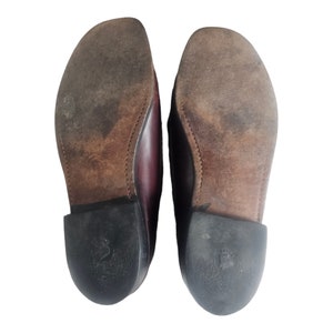 May include: A pair of brown leather loafers with black soles. The soles have a textured pattern and the shoes are worn.