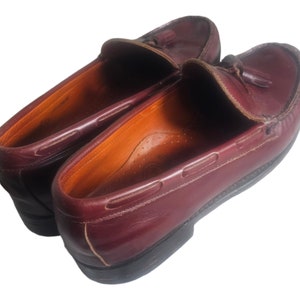 May include: A pair of burgundy leather loafers with tassels. The loafers have a classic design and are made of high-quality leather.