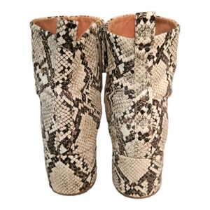 May include: A pair of ankle boots with a snakeskin pattern. The boots are beige and brown with a pointed toe and a block heel.