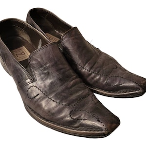May include: A pair of black leather slip-on shoes with pointed toes and decorative stitching. The shoes have a  "N" logo on the inside of the left shoe.