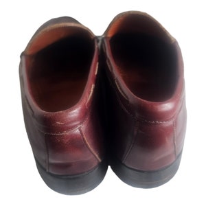 May include: A pair of burgundy leather loafers with a rounded toe and a slightly pointed heel.