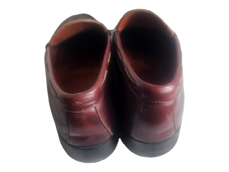 May include: A pair of burgundy leather loafers with a rounded toe and a slightly pointed heel.