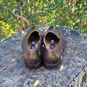 Pode incluir: Um par de sapatos de couro marrom com bico fino e design de deslizamento. Os sapatos t&ecirc;m um forro de couro marrom e uma sola de borracha.