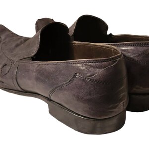 May include: A pair of dark brown leather loafers with a pointed toe and a decorative stitch pattern. The loafers have a slip-on design and a leather sole.