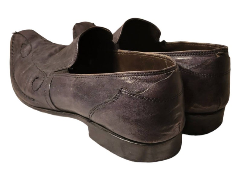 May include: A pair of dark brown leather loafers with a pointed toe and a decorative stitch pattern. The loafers have a slip-on design and a leather sole.