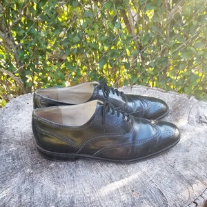 Puede incluir: Un par de zapatos negros de cuero con cordones y detalles de punta de ala. Los zapatos tienen un dise&ntilde;o cl&aacute;sico de brogue y est&aacute;n en buen estado.