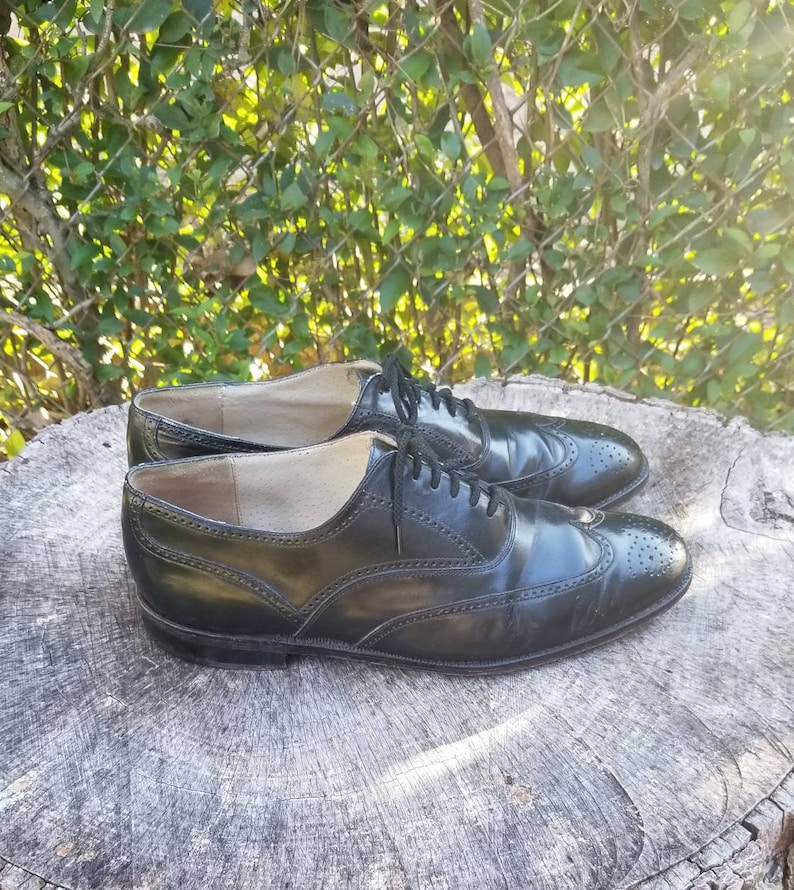 Puede incluir: Un par de zapatos negros de cuero con cordones y detalles de punta de ala. Los zapatos tienen un dise&ntilde;o cl&aacute;sico de brogue y est&aacute;n en buen estado.