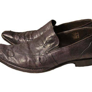May include: A pair of dark brown leather slip-on shoes with pointed toes and decorative stitching. The shoes have a leather sole and a low heel.