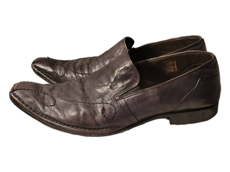 May include: A pair of dark brown leather slip-on shoes with pointed toes and decorative stitching. The shoes have a leather sole and a low heel.