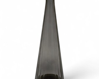 May include: A tall, conical glass vase in a translucent smoky grey hue. The vessel features a slender neck with a flared rim and a wide, circular base. The exterior surface is defined by vertical, recessed fluting that runs from the base upwards.