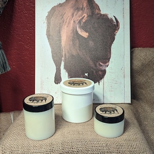 May include: Three white jars with black lids and a brown buffalo design on the lid. The jars are sitting on a brown burlap surface in front of a white canvas with a brown buffalo illustration.