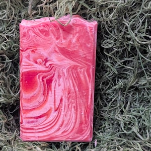 Può includere: Una saponetta artigianale con un motivo a spirale in tonalità rosa e rosso.