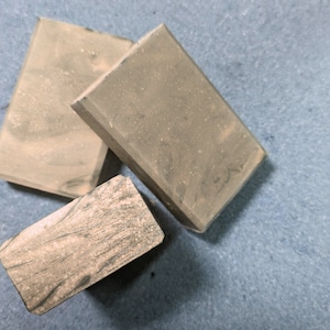 May include: Three rectangular blocks of brown and gray marble. The blocks are stacked on top of each other.