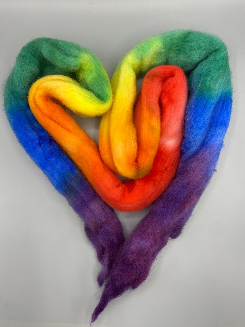 May include: A heart-shaped arrangement of colorful wool roving in shades of purple, blue, green, yellow, orange, and red.
