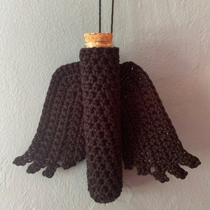 May include: A brown crocheted angel wing bottle holder with a glass bottle and cork stopper.