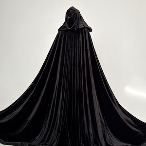 Gothic black velvet hooded cloak with luxurious flowing fabric and dramatic oversized hood. Handmade Halloween cape created individually according to customer height for elegant floor length movement and premium silhouette. Perfect gothic witch cloak for vampire costume, cosplay events, fantasy fashion styling, dark feminine aesthetic and renaissance inspired outfits.