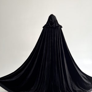 Elegant black hooded velvet cloak inspired by gothic fashion, dark witch aesthetics and Halloween costume styling. Handmade long velvet cape with hidden arm slits and premium flowing fabric designed individually according to customer height. Perfect vampire cloak for cosplay, renaissance fairs, fantasy themed photography and dramatic gothic fashion looks.