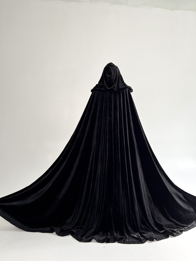 Elegant black hooded velvet cloak inspired by gothic fashion, dark witch aesthetics and Halloween costume styling. Handmade long velvet cape with hidden arm slits and premium flowing fabric designed individually according to customer height. Perfect vampire cloak for cosplay, renaissance fairs, fantasy themed photography and dramatic gothic fashion looks.