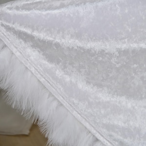 Luxurious white hooded cloak made from soft velvet fabric with elegant feather trim and dramatic flowing silhouette. Handmade fantasy cape inspired by cinematic fantasy fashion, medieval aesthetics and artistic styling. Perfect for cosplay events, renaissance fairs, editorial photography and fantasy inspired special occasions.