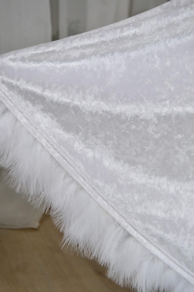 Luxurious white hooded cloak made from soft velvet fabric with elegant feather trim and dramatic flowing silhouette. Handmade fantasy cape inspired by cinematic fantasy fashion, medieval aesthetics and artistic styling. Perfect for cosplay events, renaissance fairs, editorial photography and fantasy inspired special occasions.