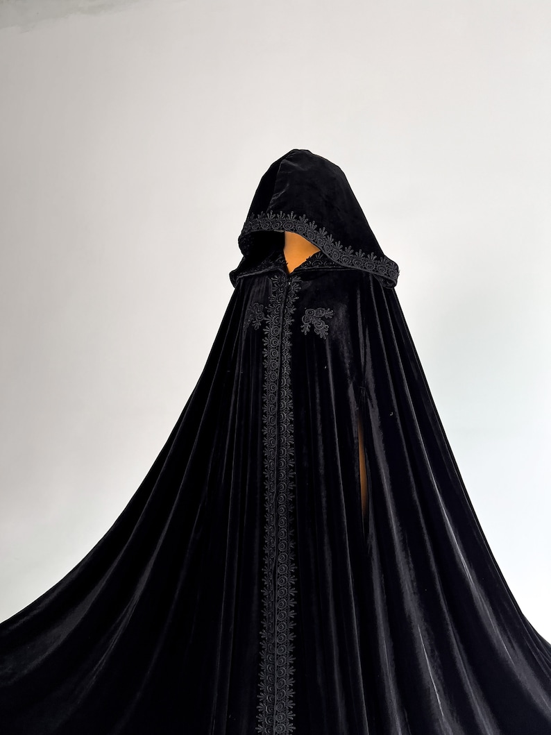 Black velvet Halloween cloak with oversized hood and luxurious flowing silhouette inspired by fantasy fashion and gothic aesthetics. Handmade floor length cape for witch costume, vampire outfit and dark fantasy cosplay. Medium density velvet fabric creates rich elegant folds and premium texture while maintaining comfort during events and photoshoots.