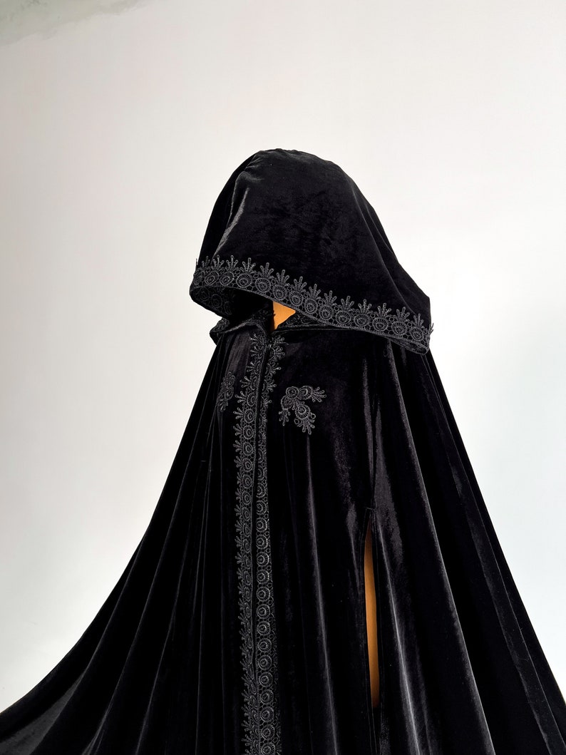 Premium black velvet hooded cape with gothic fantasy inspired silhouette and luxurious flowing movement. Handmade Halloween cloak designed individually for each customer according to height and preferred length. Elegant witch cloak with hidden arm slits and soft medium weight velvet fabric perfect for cosplay, vampire outfits and gothic themed events.