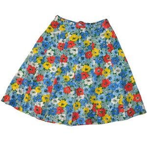 Puede incluir: Una falda de estampado floral azul, amarillo, rojo y blanco. La falda es plisada y tiene una cintura alta.