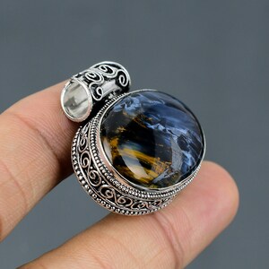 May include: Silver pendant with an oval blue and gold tiger's eye gemstone set in a decorative silver frame.
