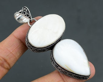 May include: A silver pendant with two white mother of pearl stones. The stones are oval and teardrop shaped and are set in intricate silver filigree.