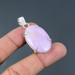 May include: A silver pendant featuring a light purple oval cabochon gemstone. The pendant has a bail for attaching to a chain.