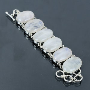 May include: A silver bracelet with six oval-shaped moonstone gemstones. The bracelet has a lobster clasp closure.